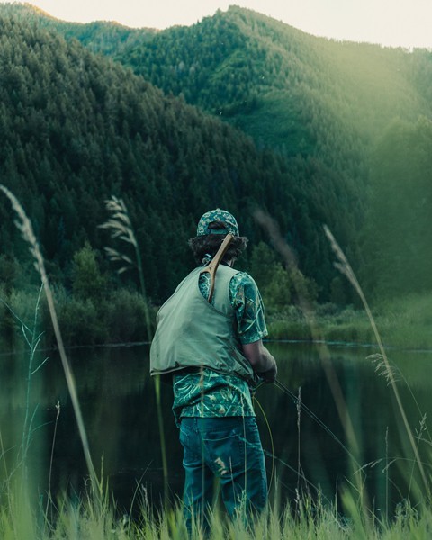 a man wearing cap is standing beside the lake